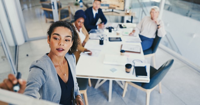 Business people brainstorming and woman writing on whiteboard